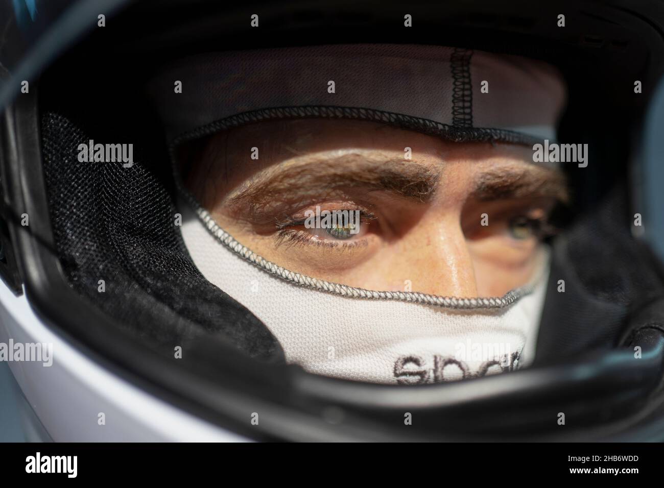Close up portrait of a handsome young man wearing a formula one racing helmet. Stock Photo