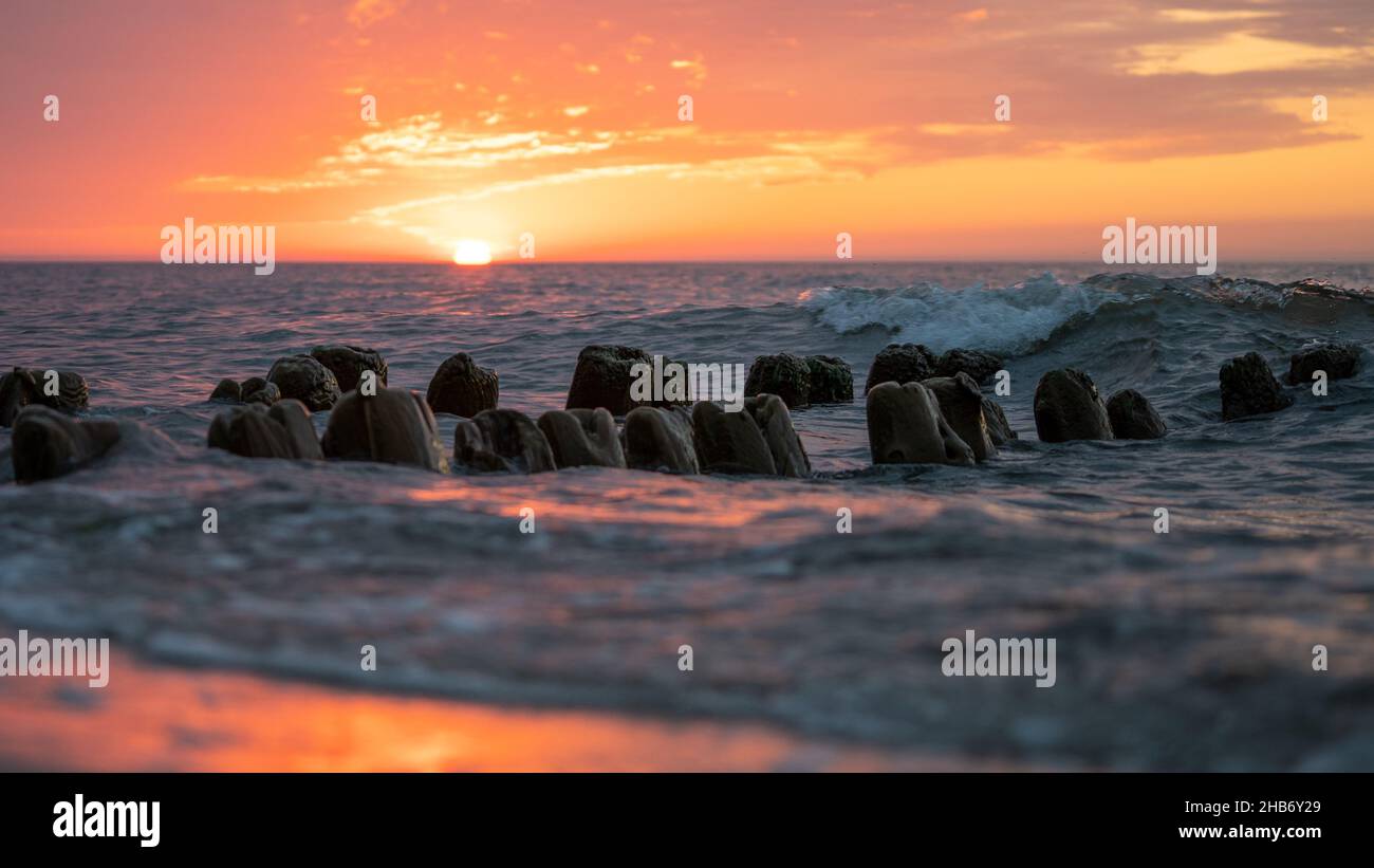Scenic view of rocks on the beach on a bright sunset sky background ...