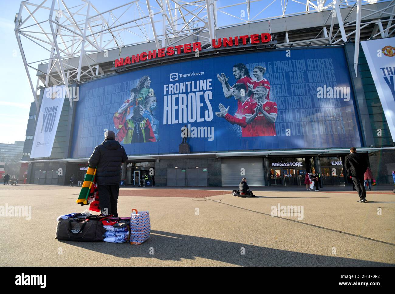 A scarf seller outside of Old Trafford Stadium, the home of Manchester United. The Premier League is under increasing pressure to suspend this weekendâ€™s entire schedule following a raft of coronavirus-enforced postponements. Five of the 10 scheduled matches across Saturday and Sunday have already been called off, taking the total number of postponed top-flight fixtures this week to nine. Picture date: Friday December 17, 2021. Stock Photo