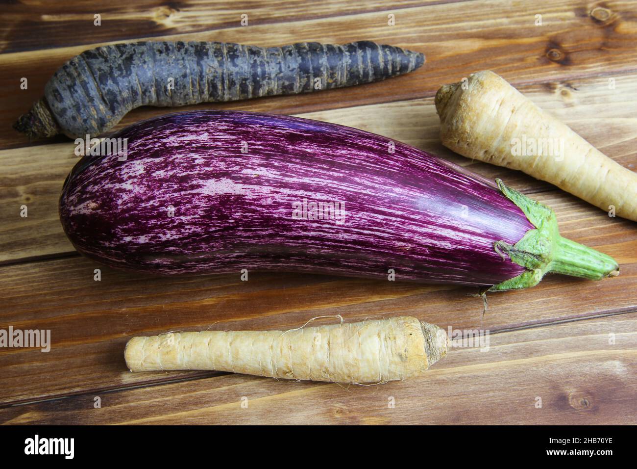 Top view on whole purple white ripe zucchini with parsley roots and black  carrot on wooden background Stock Photo - Alamy