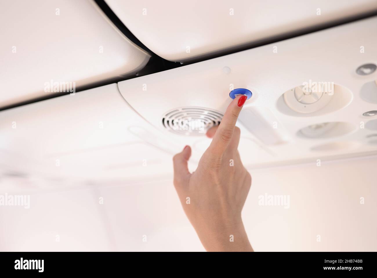 Airplane passenger female press blue button on plane with finger