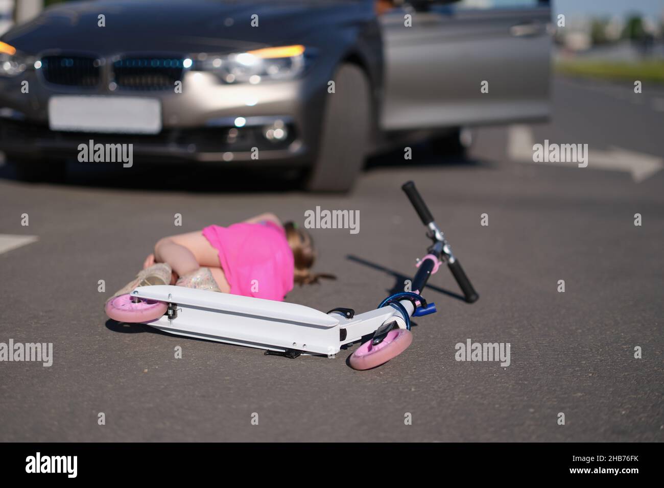 Little girl on scooter hit on road by automobile, road accident Stock