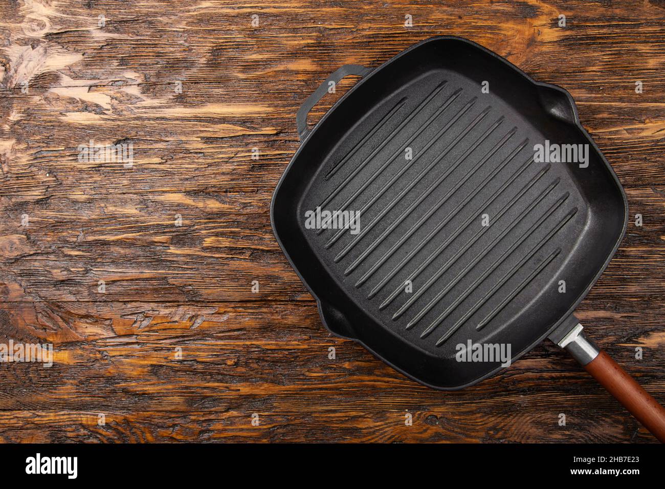https://c8.alamy.com/comp/2HB7E23/an-empty-black-cast-iron-grill-pan-for-cooking-delicious-meat-wood-background-space-for-text-top-view-2HB7E23.jpg
