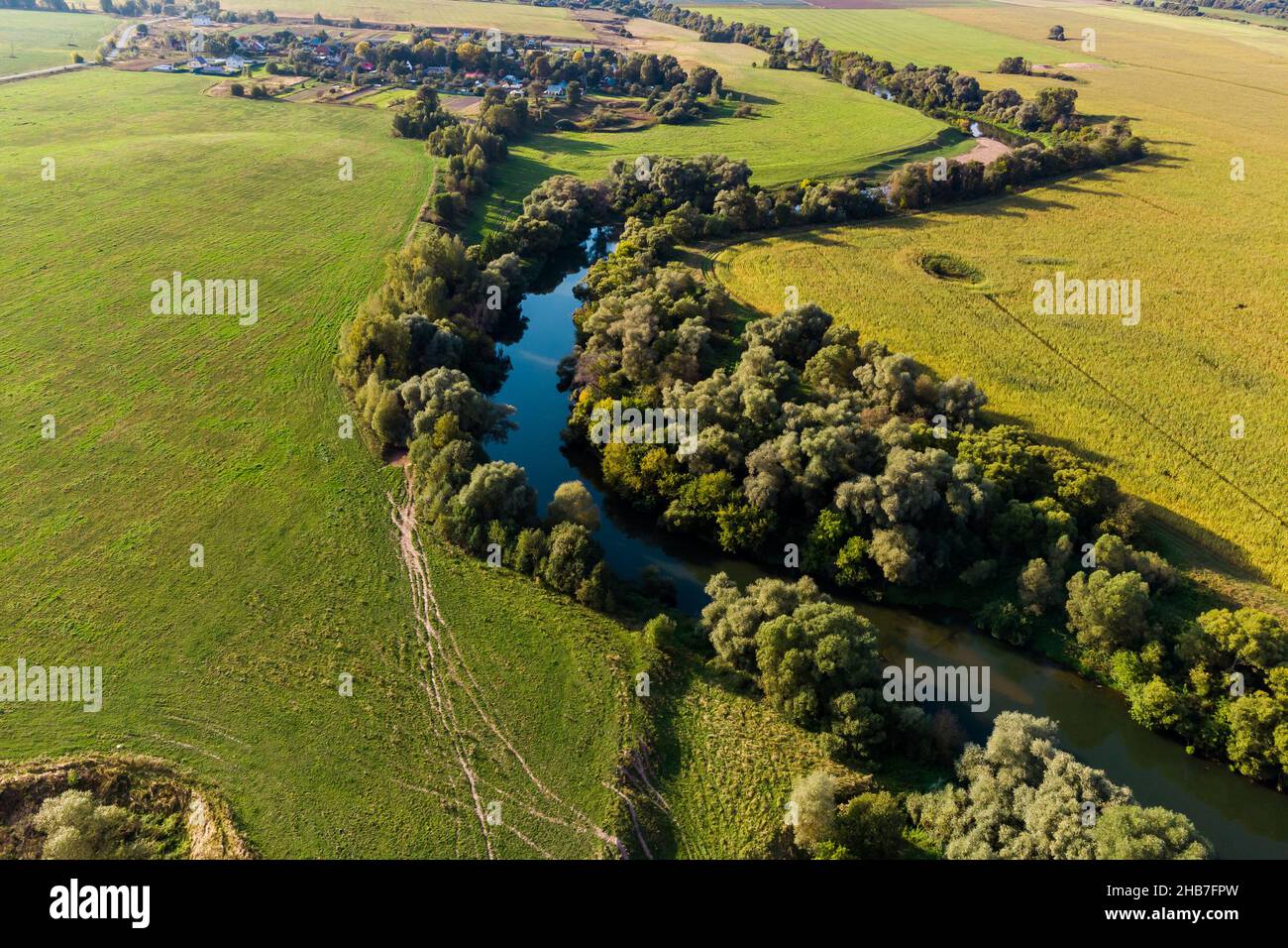 Bird'seye view of a bend in a river flowing through agricultural