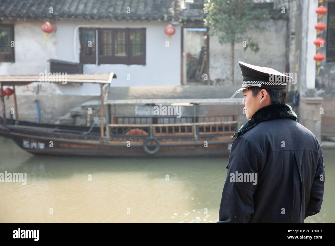 Policeman observing traffic on a canal in the water village of Xitang, China Stock Photo