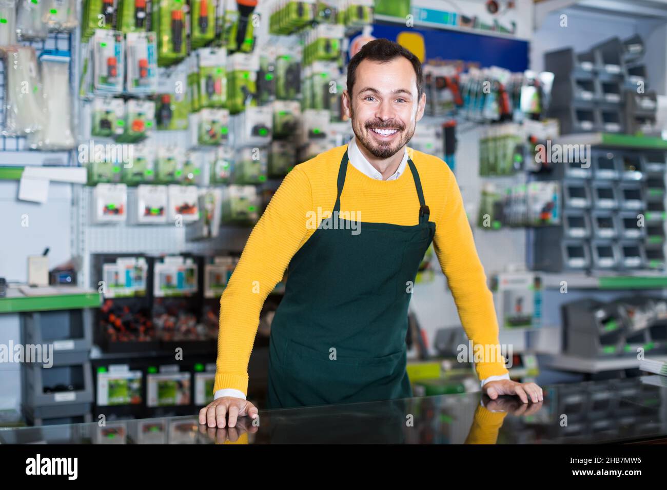 active male seller showing assortment in garden equipment shop Stock