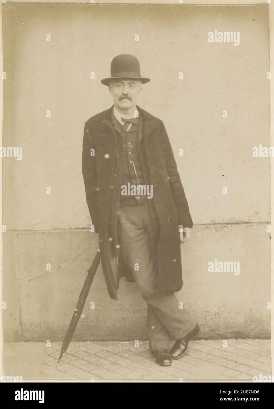 Portrait of a standing French man wearing a long coat, a hat and 