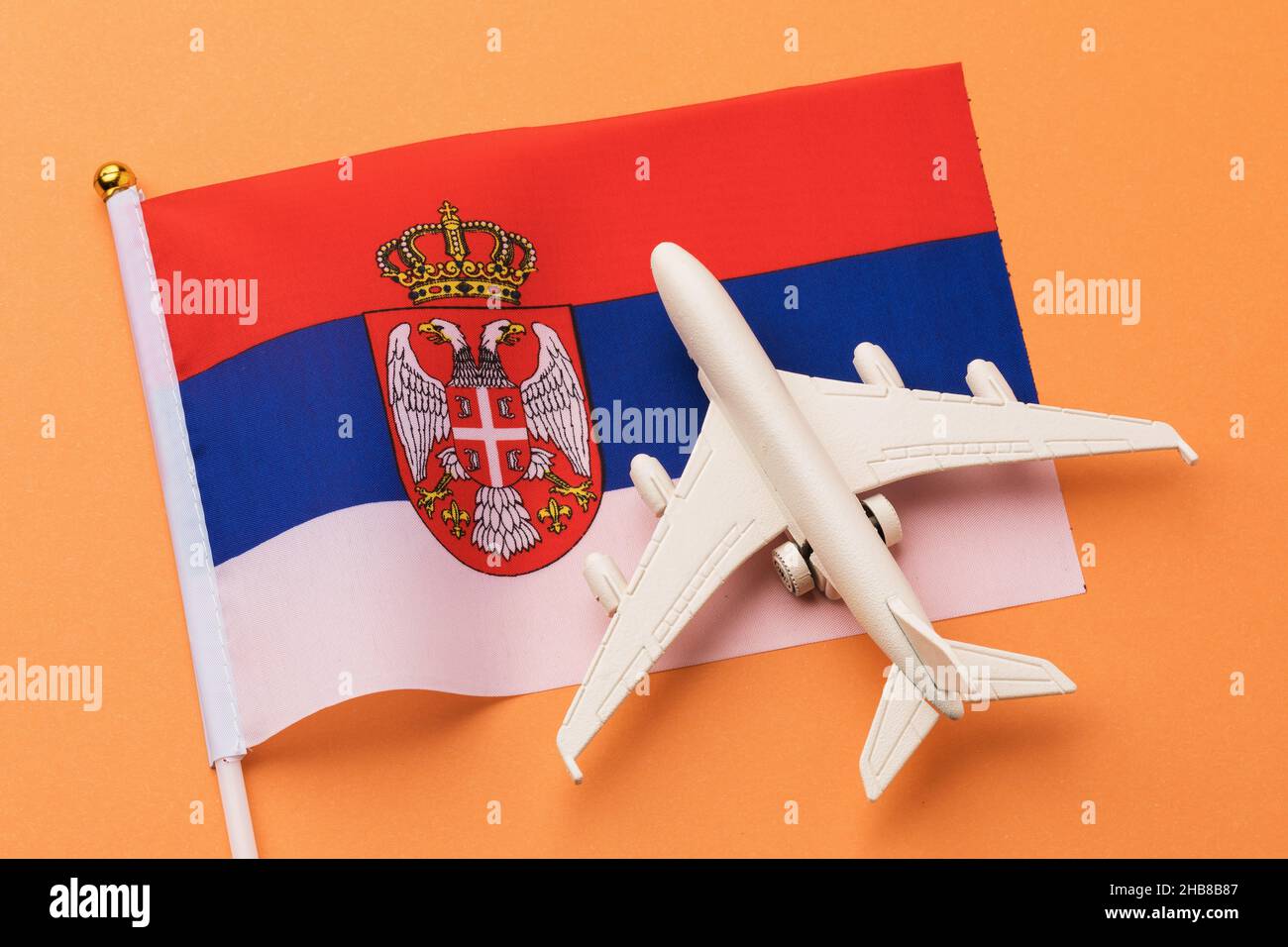 Serbian flag and toy plane on a colored background, concept on the theme of travel to Serbia Stock Photo
