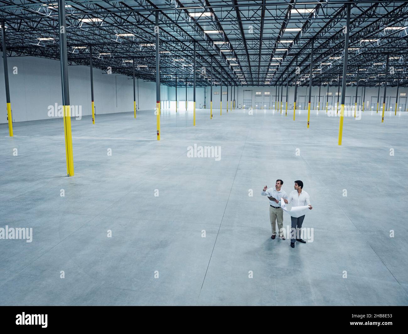 Architects with blueprint talking in empty warehouse Stock Photo