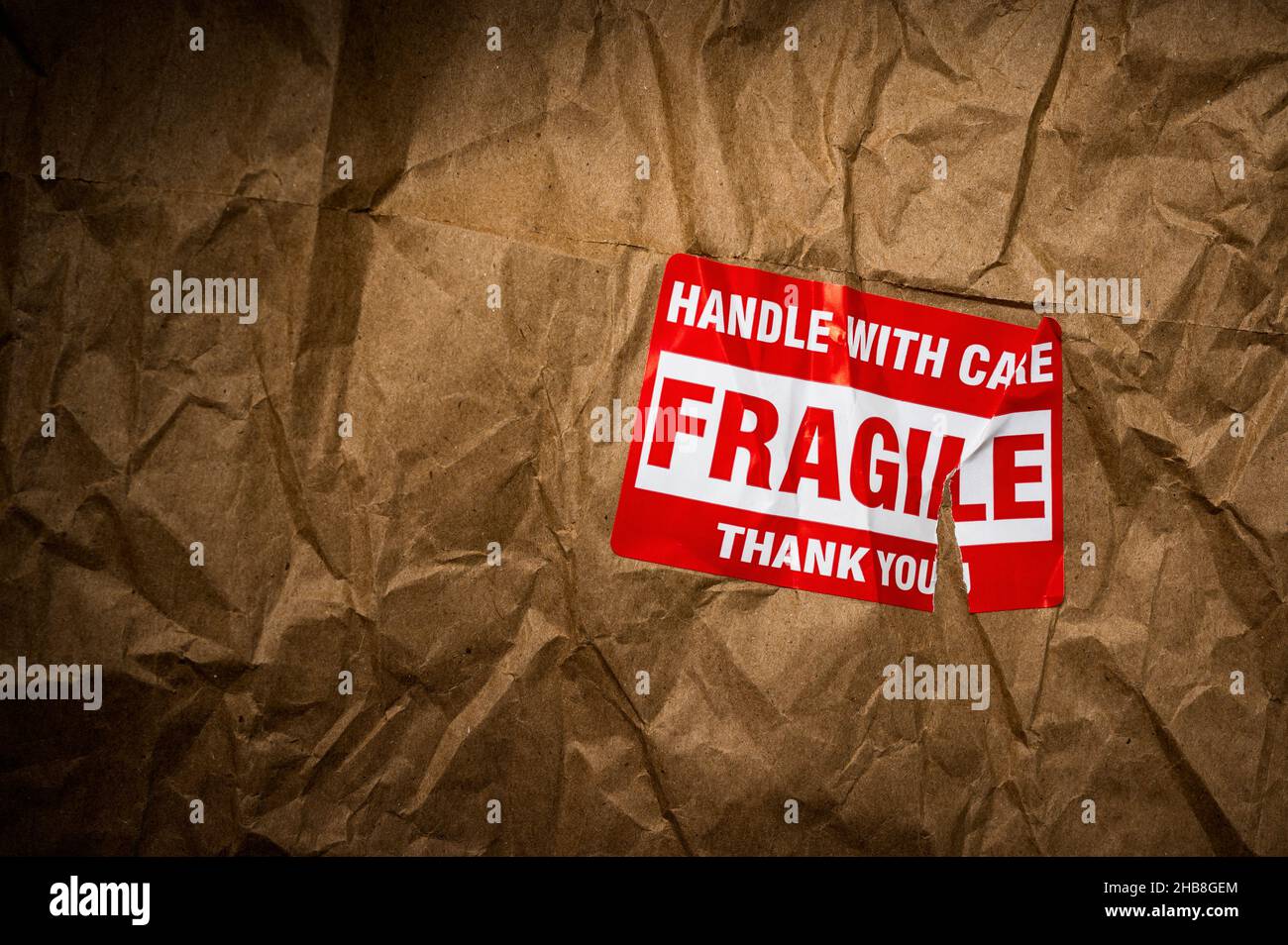 Fragile handle with care sticker on crushed package Stock Photo