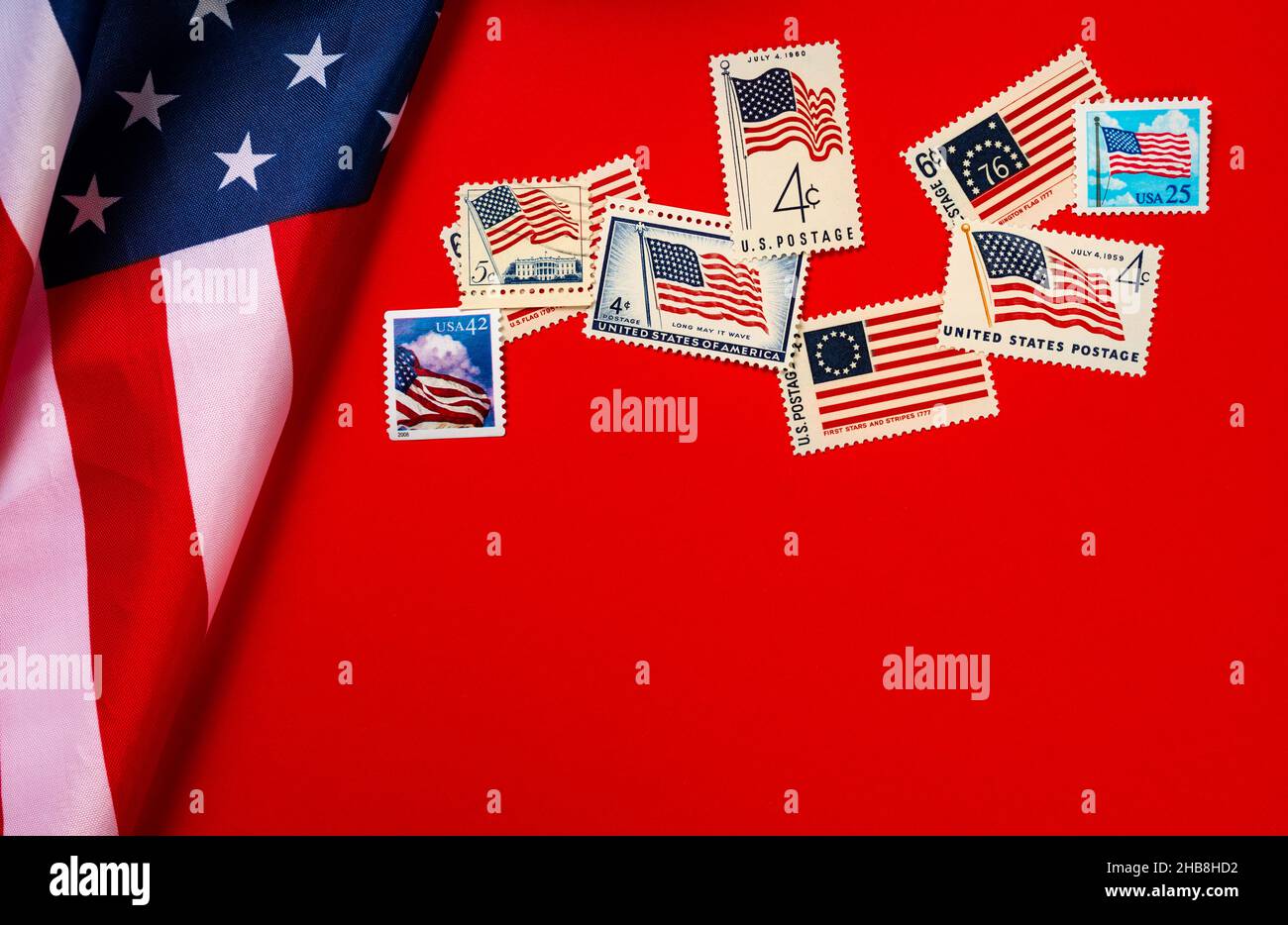 Retro postage stamps and American flag against red background Stock