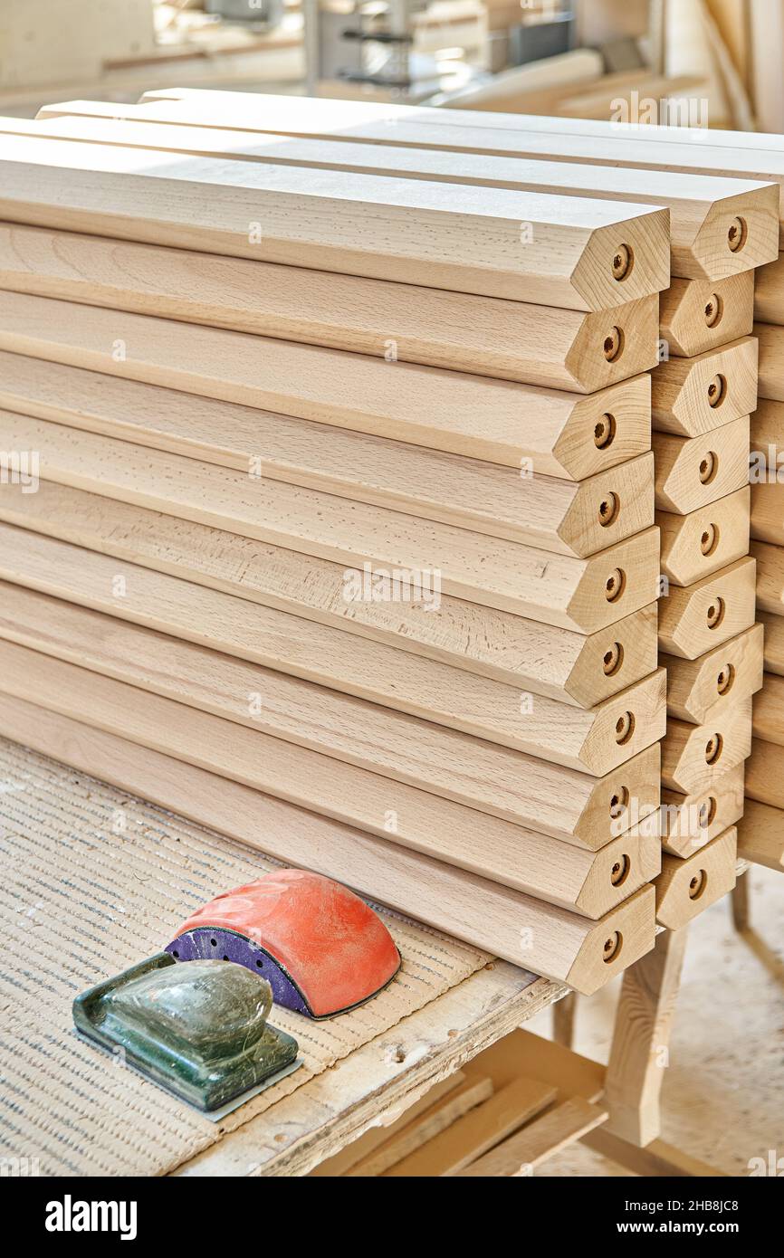 High stacks of new tables legs made of solid beechwood material on workbench in sanding carpentry workshop extreme closeup Stock Photo