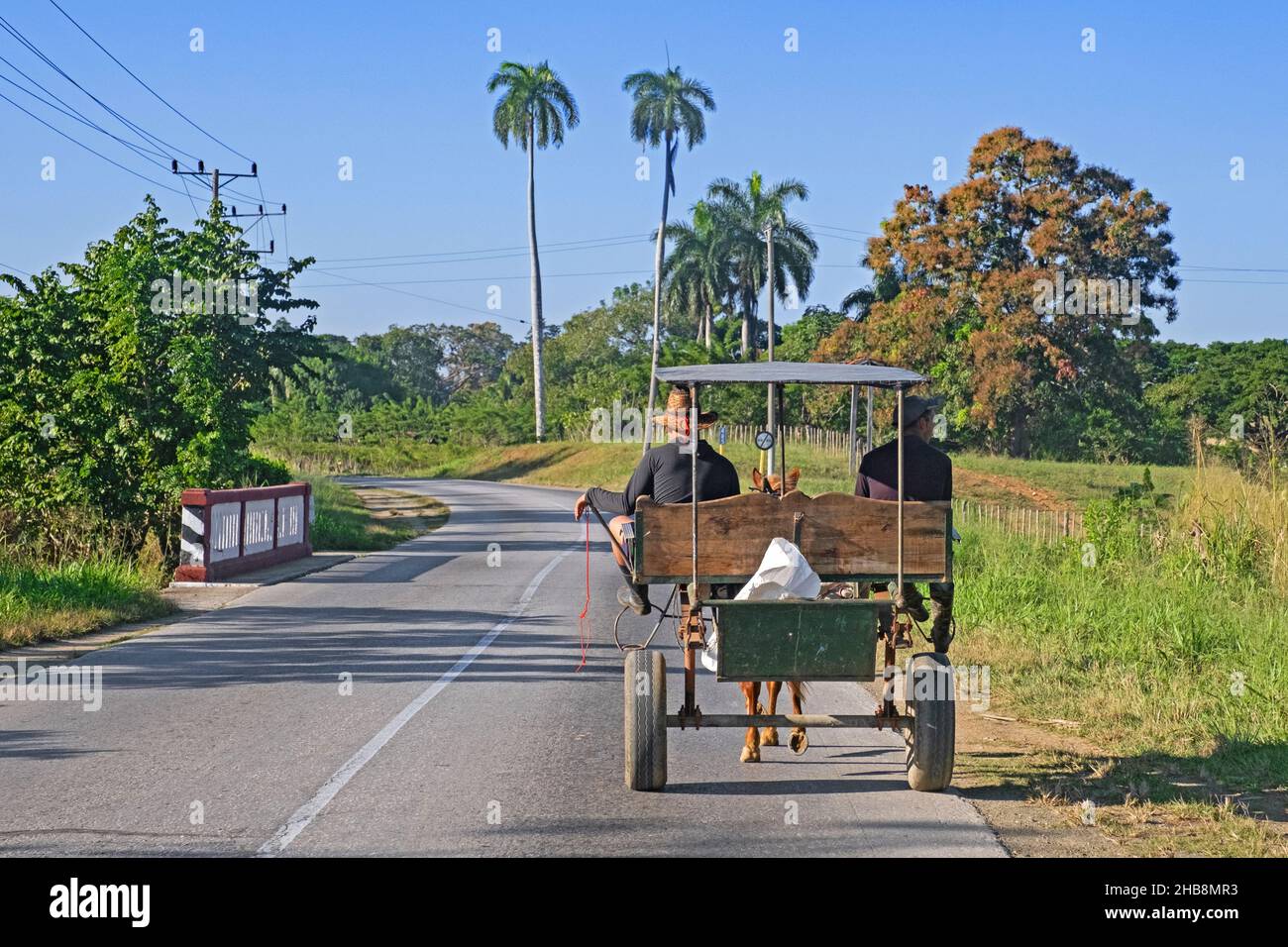 Two Cubans riding in horse-drawn carriage along the Circuito Sur / CS, west-east highway in the Sancti Spíritus Province on the island Cuba, Caribbean Stock Photo
