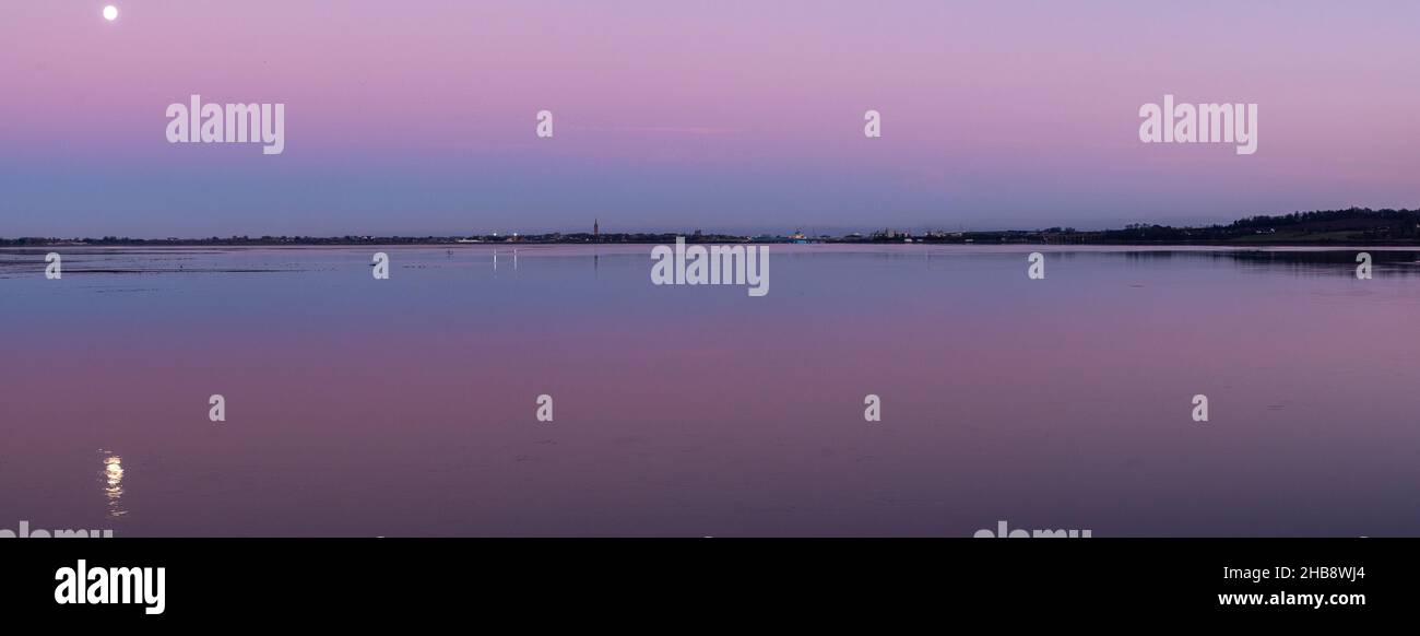 Angus, UK. 17th Dec, 2021. UK Weather, Montrose Basin, Angus, Scotland, UK 17th of Dec 2021: Pictured - The Montrose basin in Angus, as the sunsets and the moon rises to take its place, leading to a dramatic sky filled with colours, as the temperature drops to -1 tonight in Montrose. Credit: Barry Nixon/Alamy Live News/Alamy Live News Stock Photo