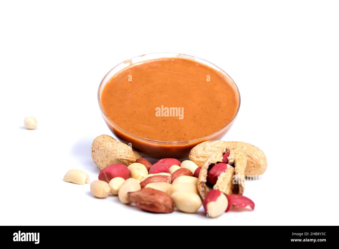 Peanut butter and peanuts in the peel scattered isolated on the white