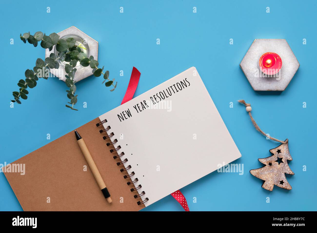 New Year resolutions. Text in spiral notepad, notebook. Tea light ...