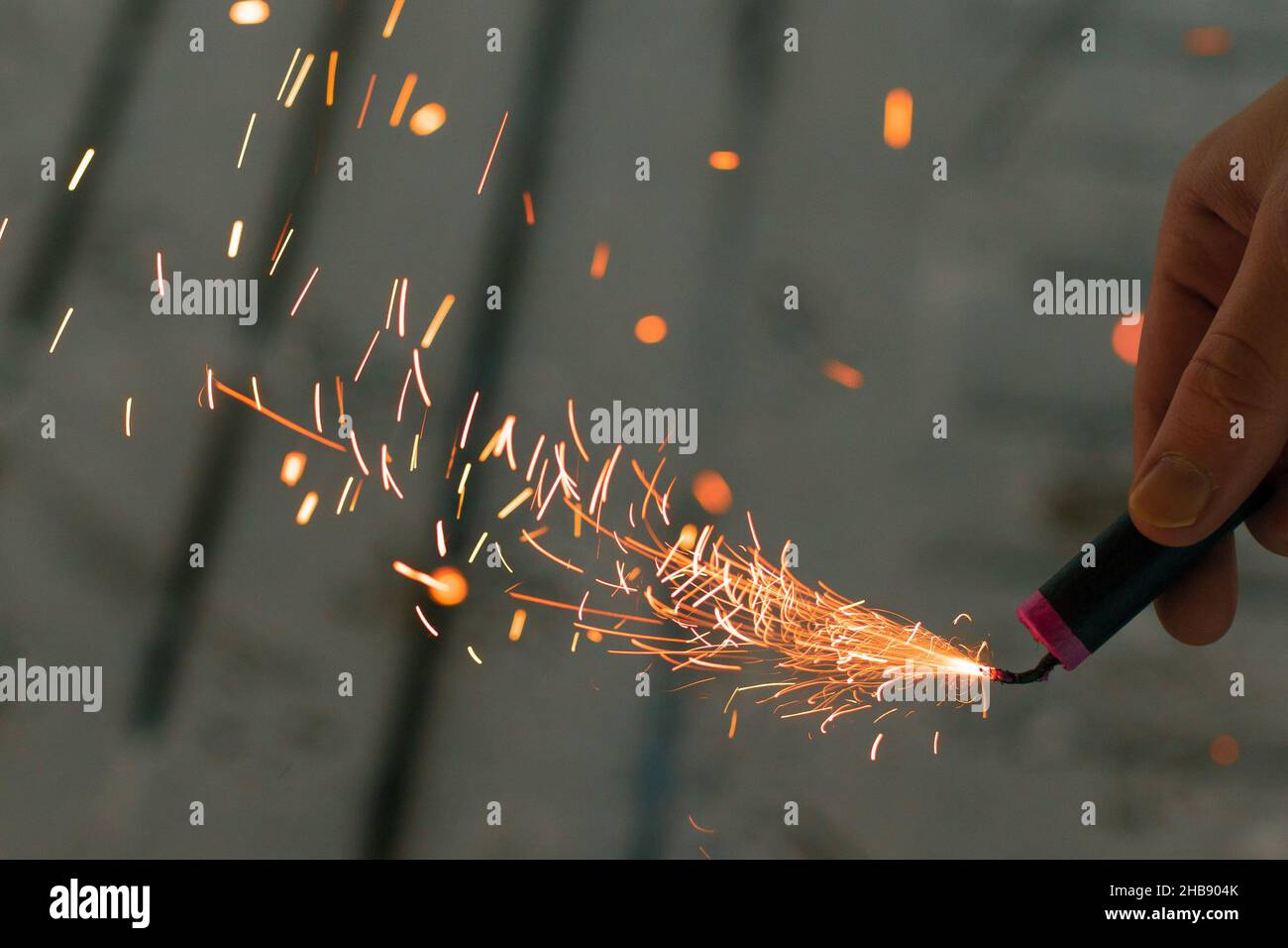 Burning Firecracker with Sparks. Guy Holding a Petard in a Hand. Loud and Dangerous New Year's Entertainment. Hooliganism with Pyrotechnics. Noise of Stock Photo