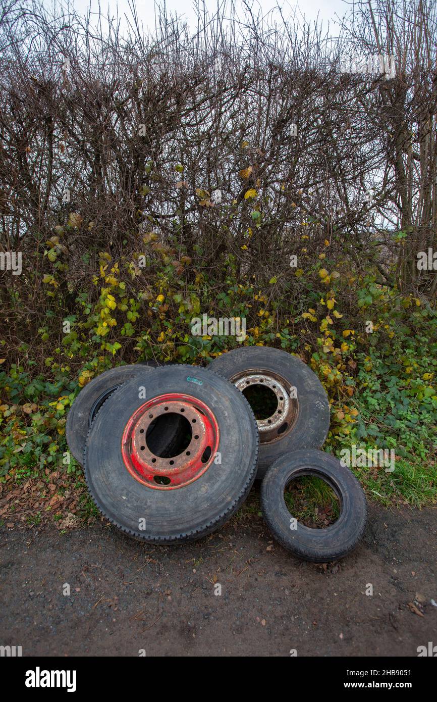 Discarded and dumped tyres lay in a hedgerow in a Worcestershire country lane causing an eyesore and possible future pollution. Stock Photo