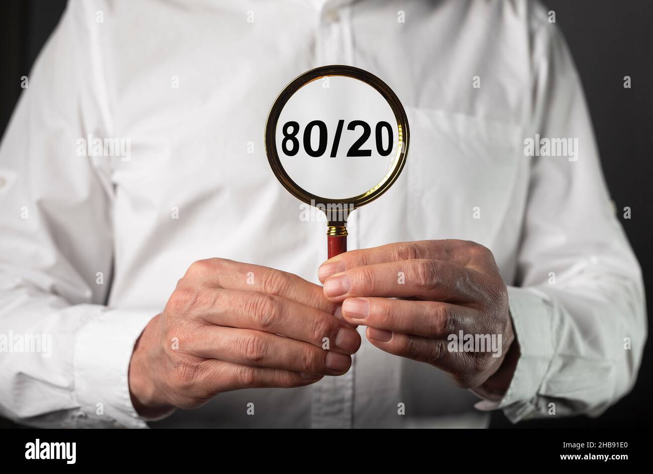 80 20 pareto principle concept, text through magnifying glass in business man hands. Stock Photo