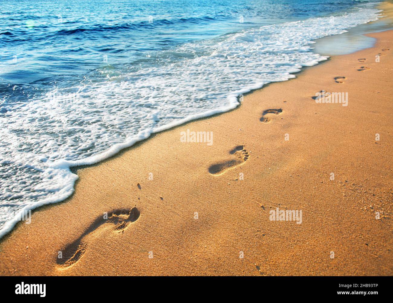 beach, wave and footprints at sunset time Stock Photo
