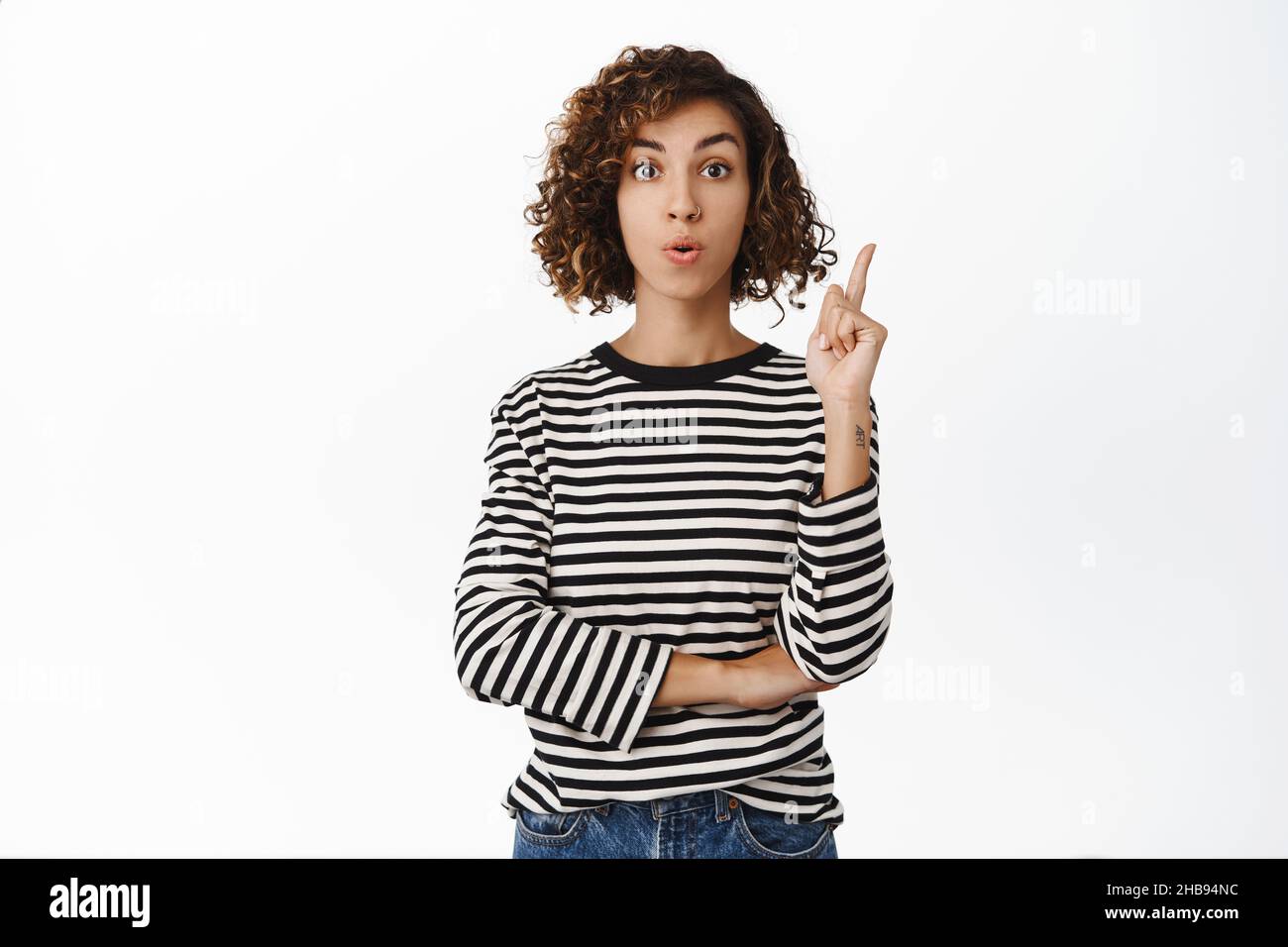 Enthusiastic middle eastern girl pointing finger up, has solution, eureka gesture, suggesting an idea or plan, standing over white background Stock Photo