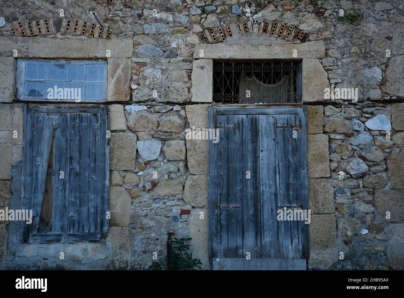 Old traditional rural house facade with a weathered stone wall and blue ...