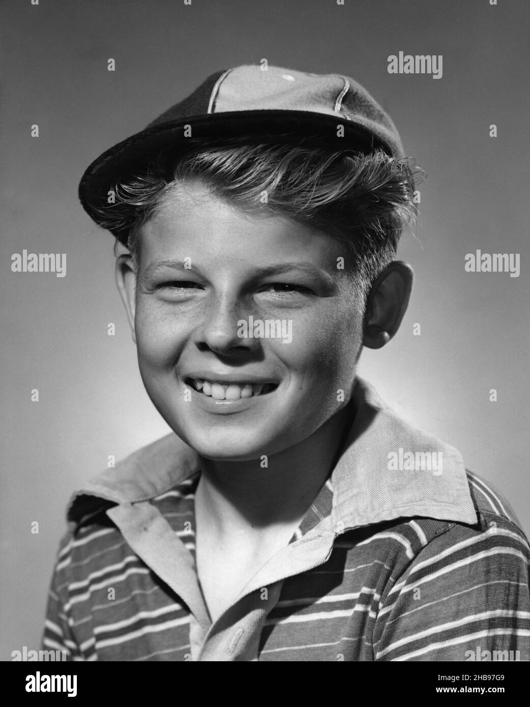 Cleancut young boy in stripped collared shirt with a baseball cap on
