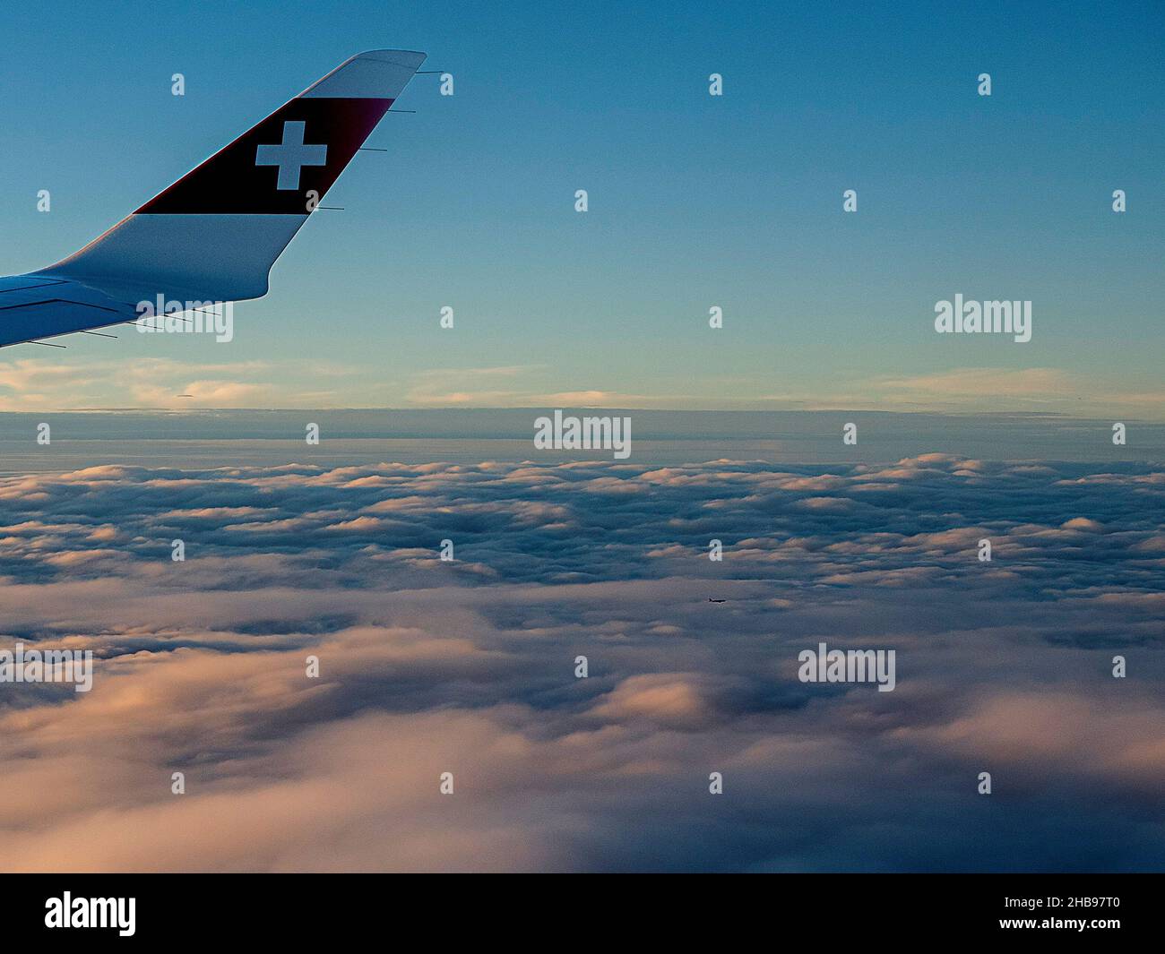 Flight view with Swiss airline logo on plane wing at sunset. Stock Photo