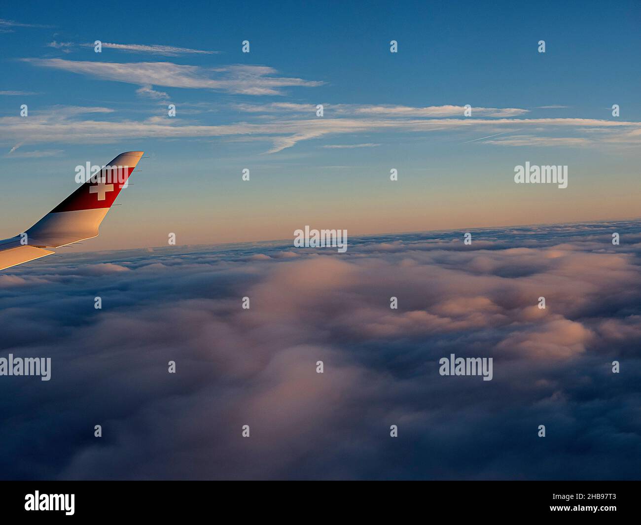 Flight view with Swiss airline logo on plane wing at sunset. Stock Photo