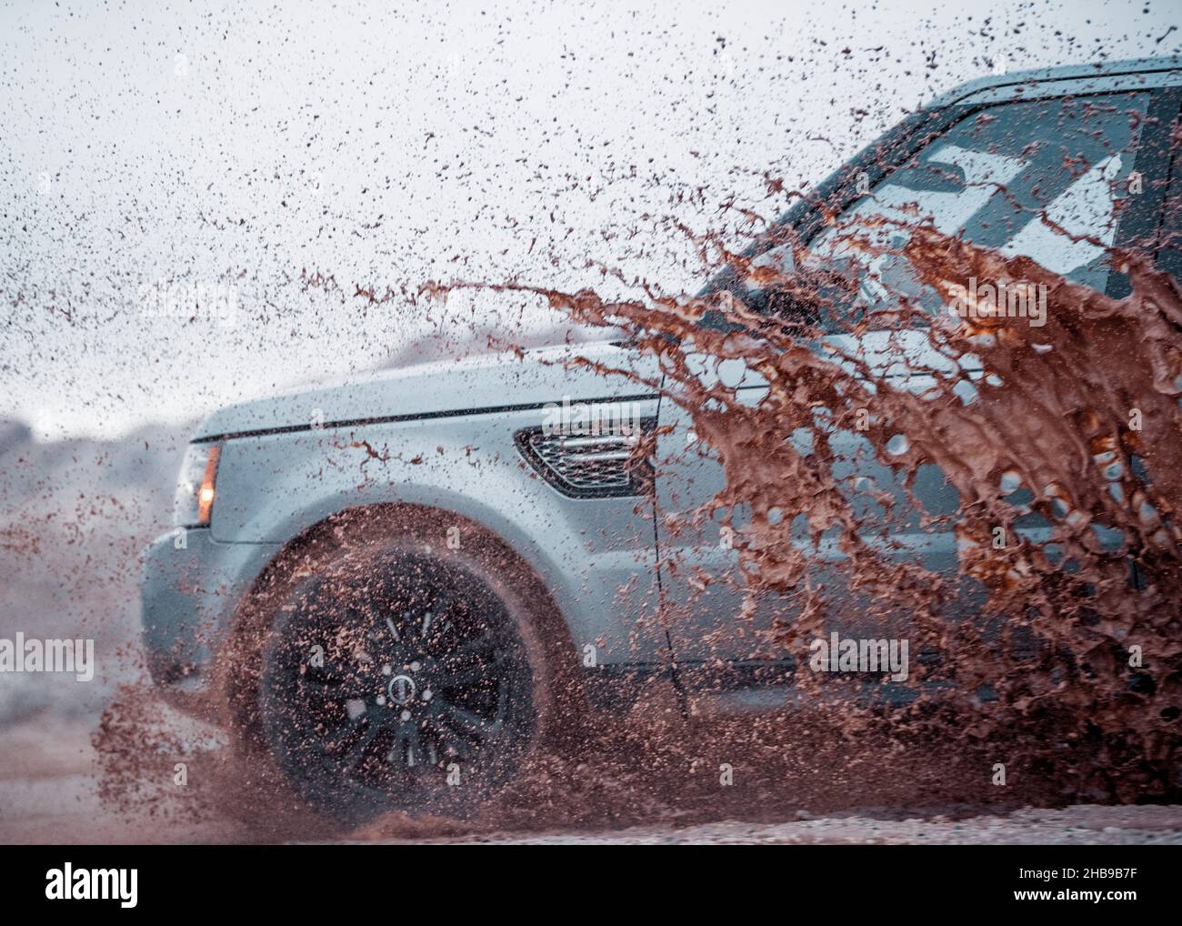 Range Rover driving through a puddle, splashing mud Stock Photo