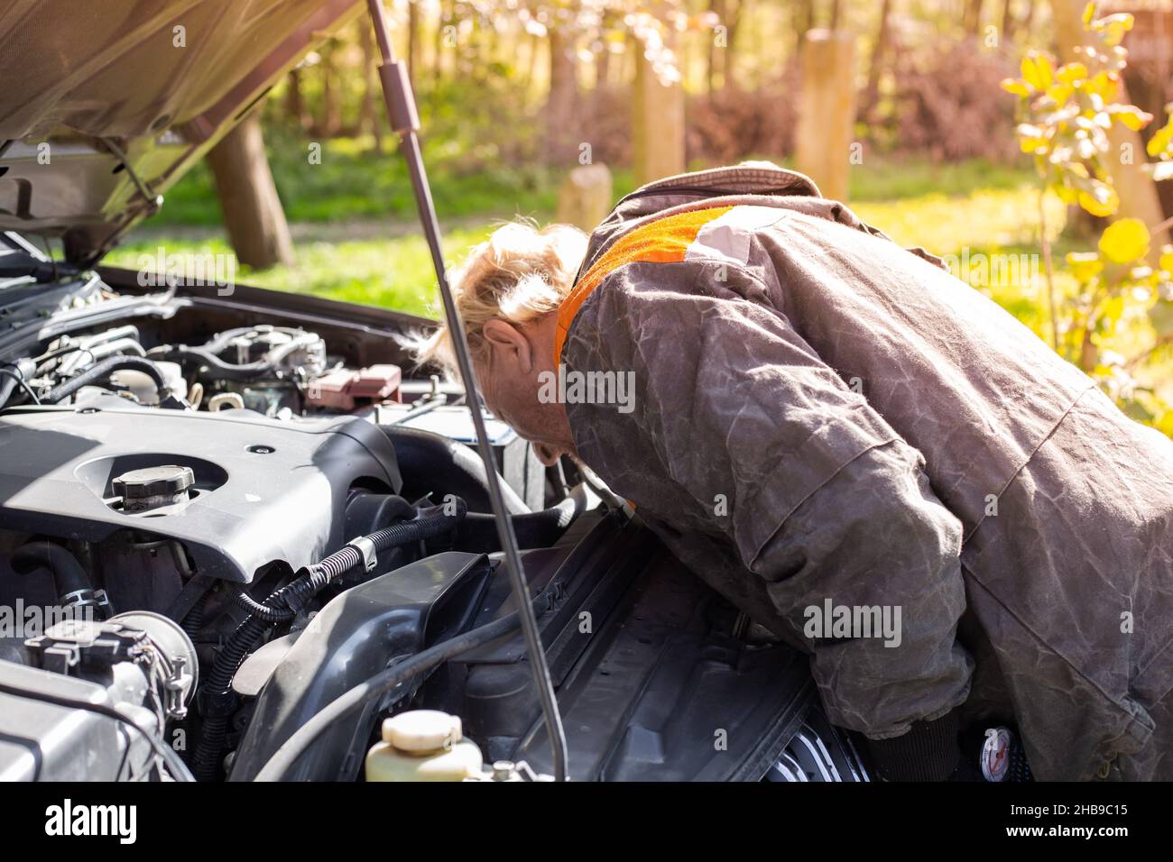 The man bent over the hood of the car and looks for a breakdown. Car