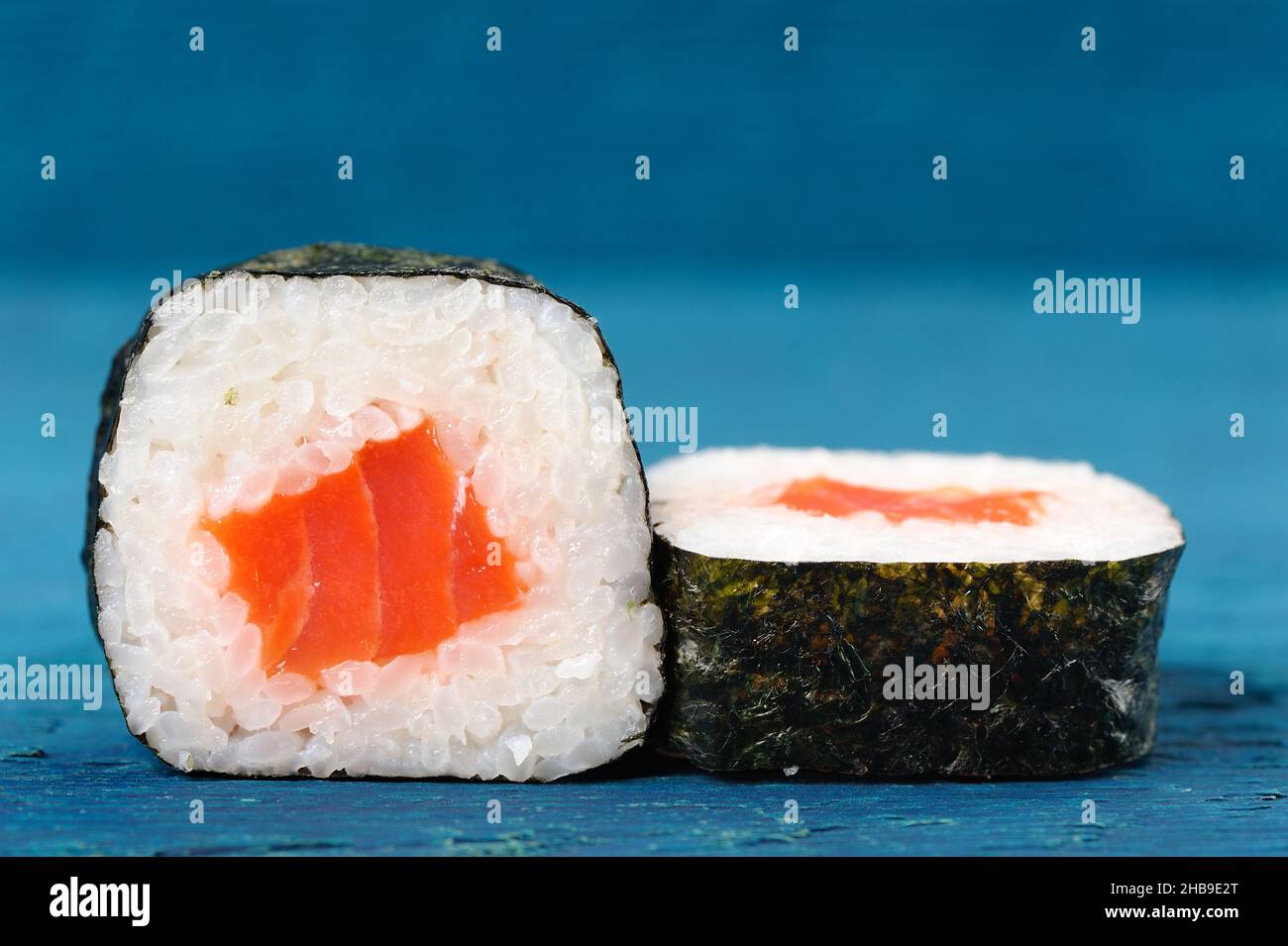 Pair of japanese rolls with salmon, rice and nori on sky blue