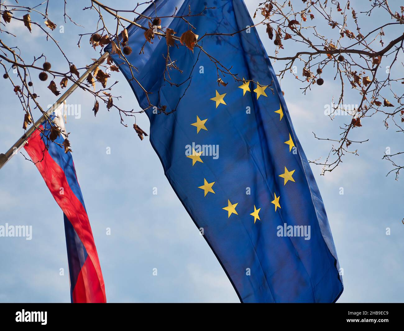 EU flag and the flag of Slovenia in the air Stock Photo