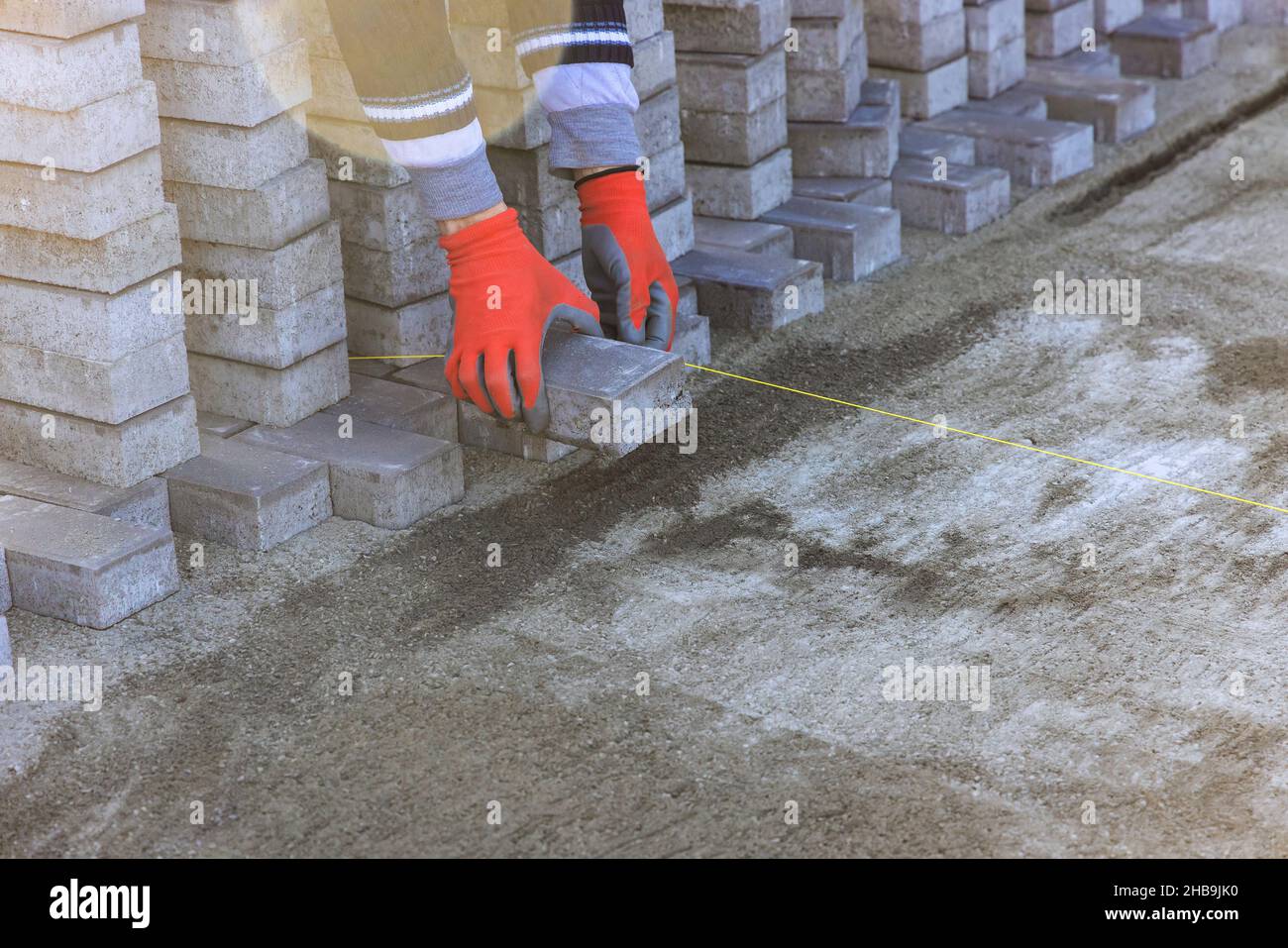 Landscaping paver worker laying paving stones on sand for sidewalk