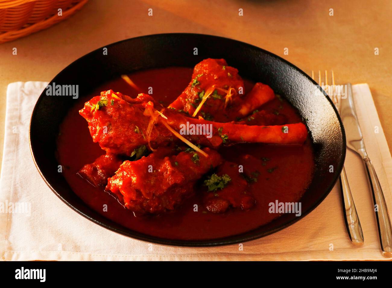 slow cooked indian lamb or mutton shank curry, also known as nalli rogan josh on dining table