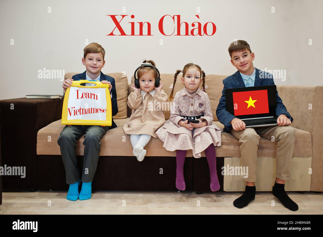 Four kids show inscription learn vietnamese. Foreign language learning concept. Xin Chao. Stock Photo