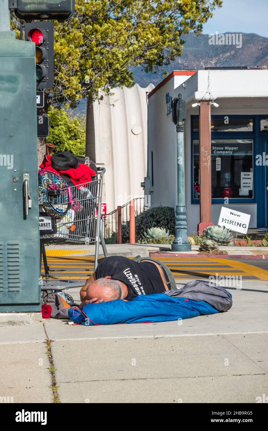 A homeless man sleeping on the sidewalk Stock Photo
