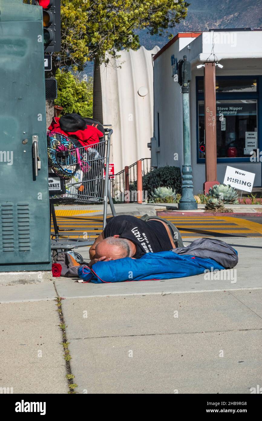 A homeless man sleeping on the sidewalk Stock Photo