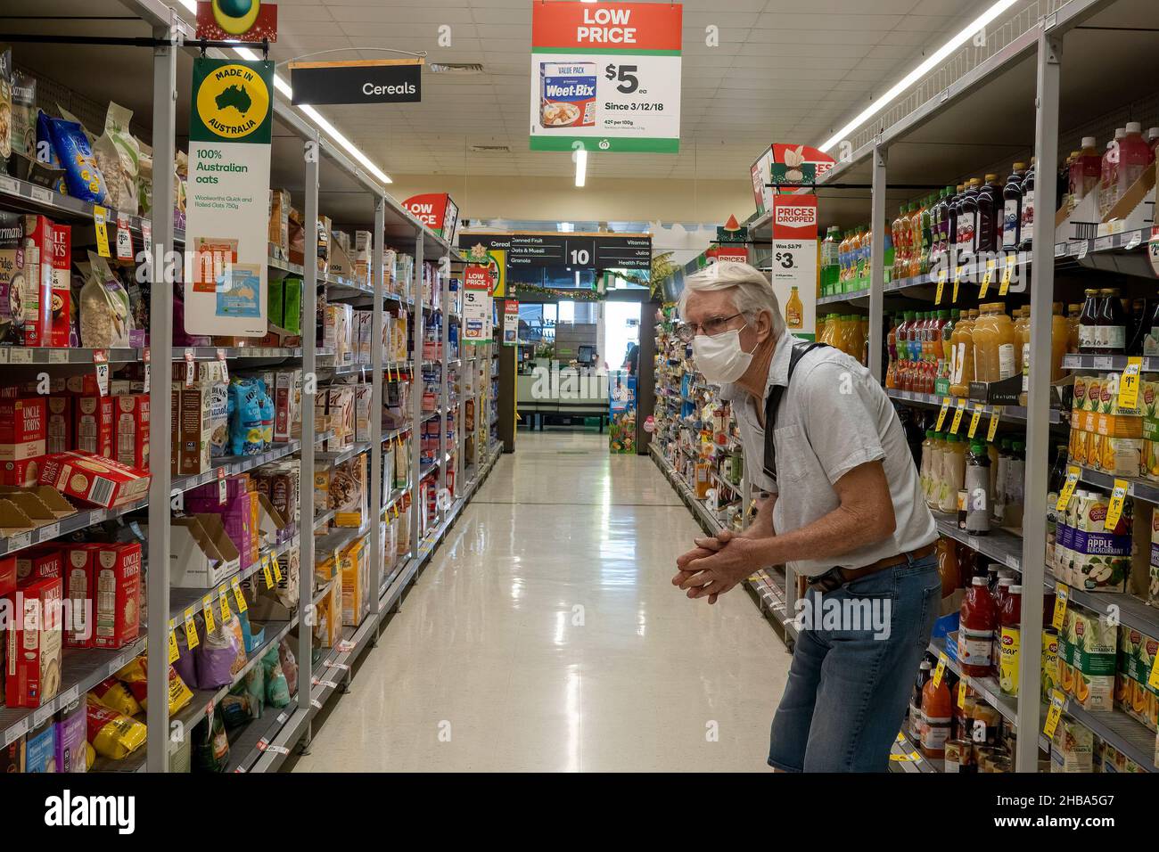 Mackay, Queensland, Australia - December 2021: Senior male retiree wearing a mask looking for the right produce in a supermarket Stock Photo