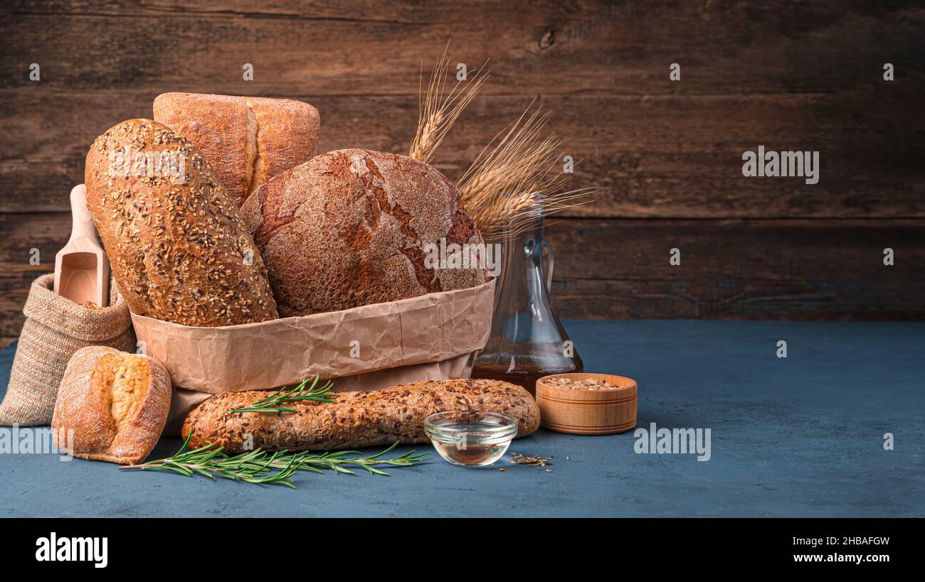 Fresh bread, butter and rosemary on a wooden background. Side view, copy space. Stock Photo