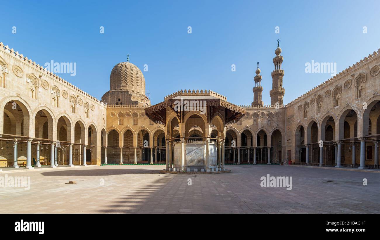 Ablution fountain mediating the courtyard of public historic mosque of Sultan al Muayyad, with background of arched corridors surrounding the courtyard, dome and minarets of the mosque, Cairo, Egypt Stock Photo