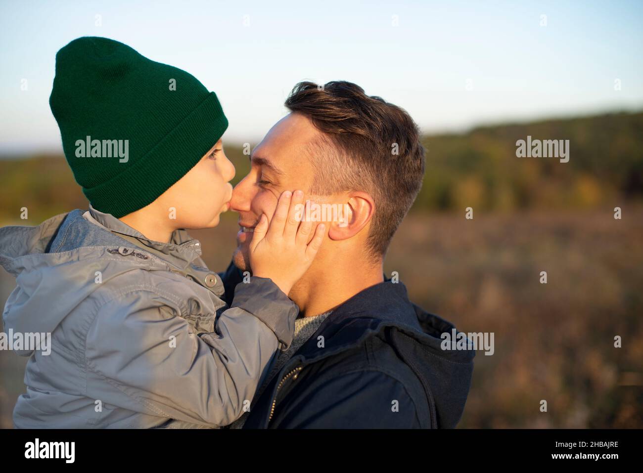 Little caucasian boy kissing his happy smiling father outdoors closeup portrait Stock Photo
