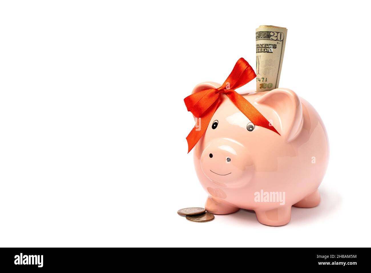 Pink piggy bank with a red bow on the ear and dollar bills inside ...