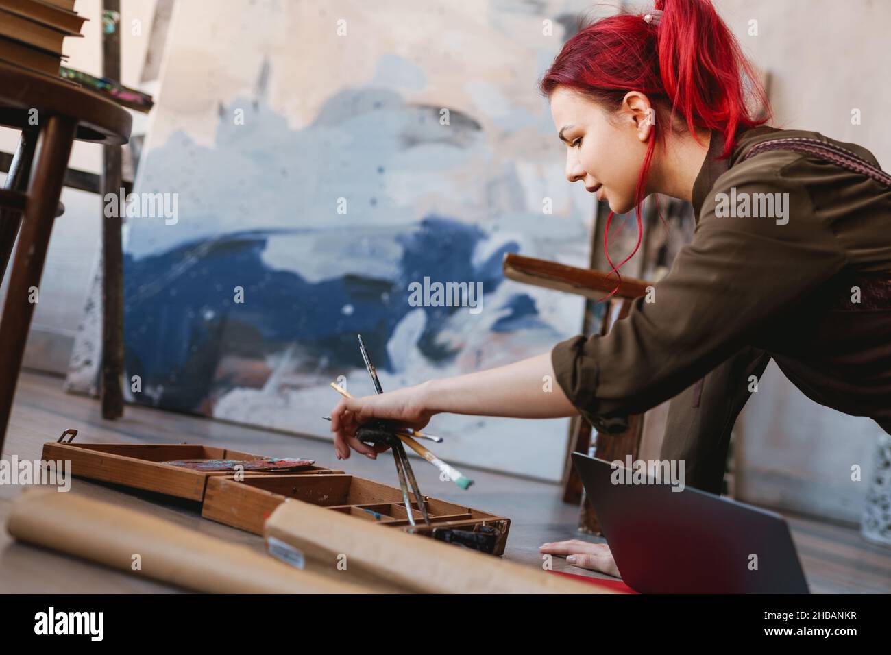 Young white woman painter in an art studio, using laptop computer for ideas Stock Photo Alamy