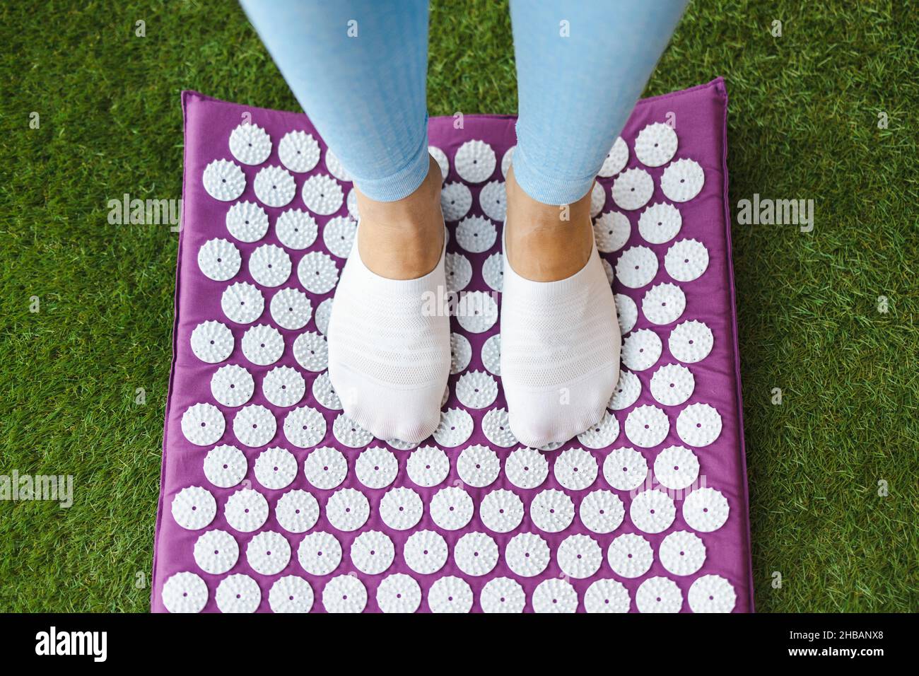 Women's feet standing on acupressure mat. Acupuncture massage Stock