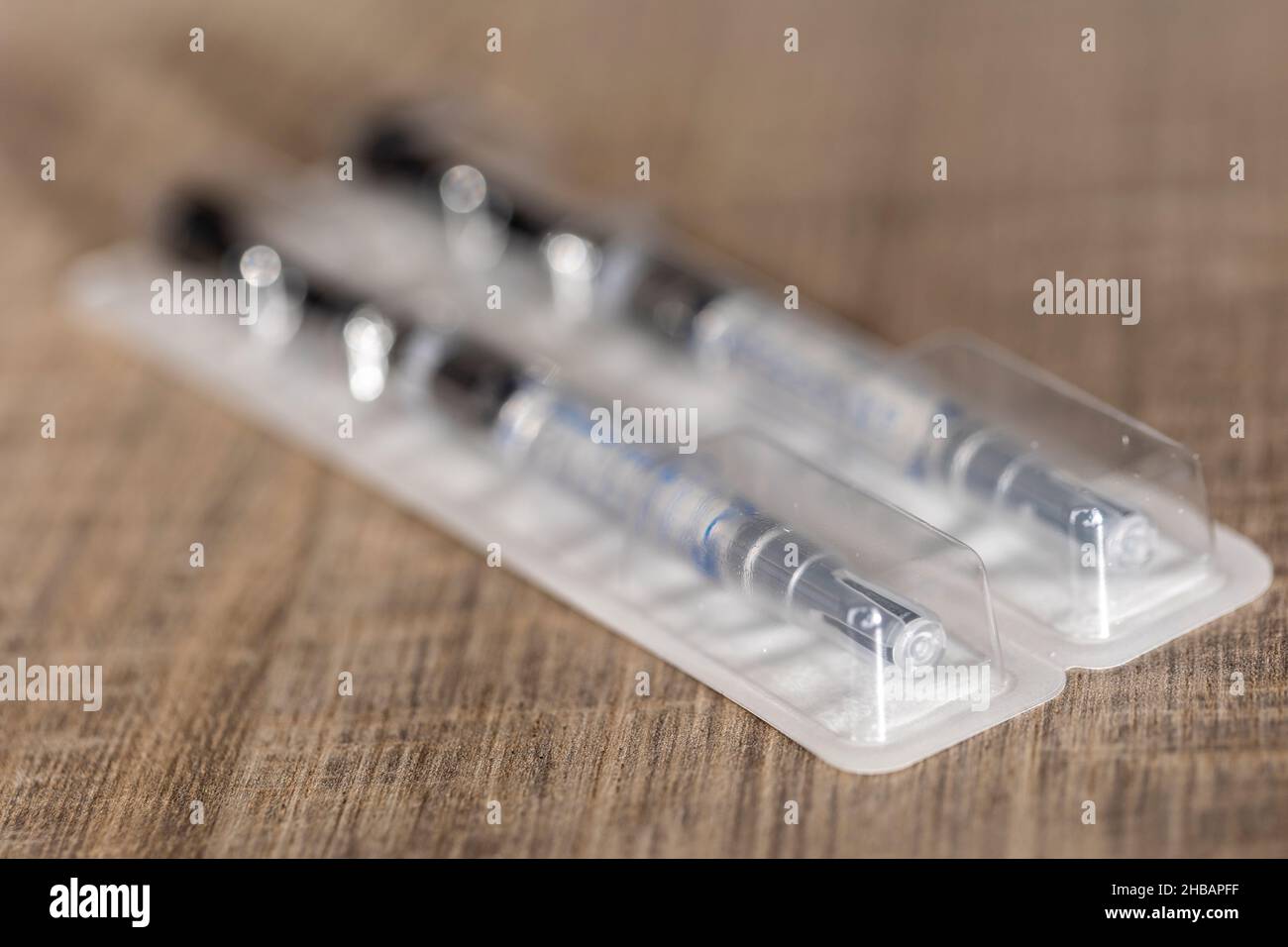 A portrait of a package with two syringes in it lying on a wooden table ...