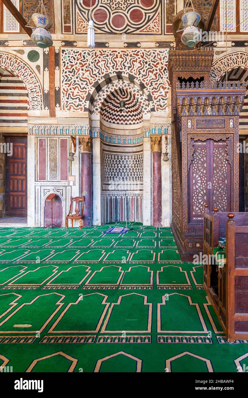 Colorful decorated marble wall with engraved Mihrab - niche - and wooden Minbar - Platform - at Mamluk era public historical mosque of Sultan al Muayyad, Old Cairo, Egypt Stock Photo