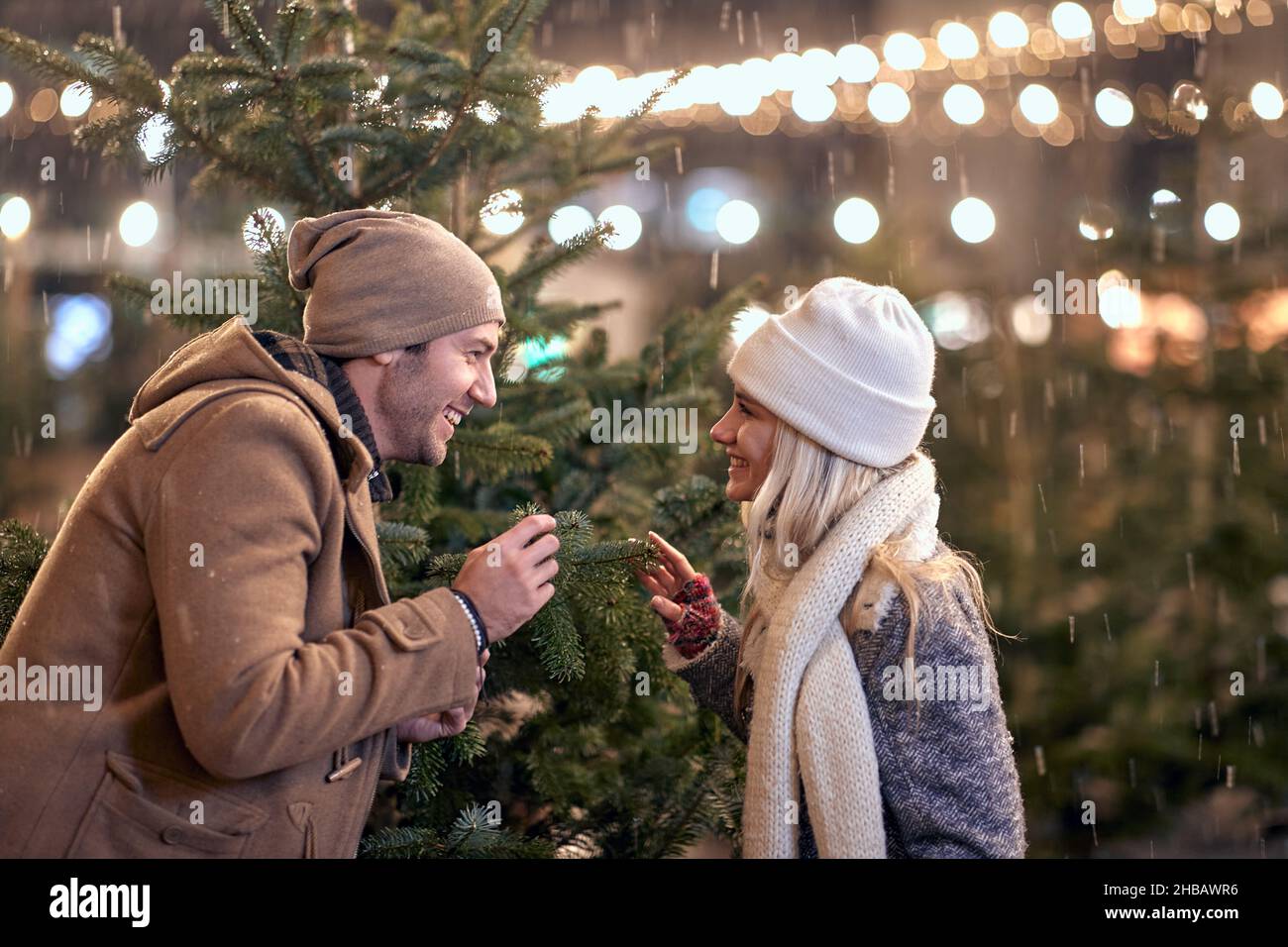 A young couple is enjoying christmas holidays while walking the city on a beautiful snowy night. Christmas, New Year, holiday, love Stock Photo