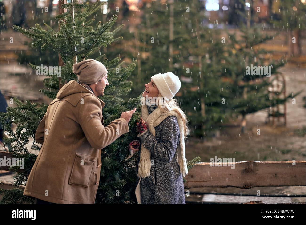 A young couple is having fun while enjoying christmas holidays and walking the city on a beautiful snowy night. Christmas, New Year, holiday, love Stock Photo