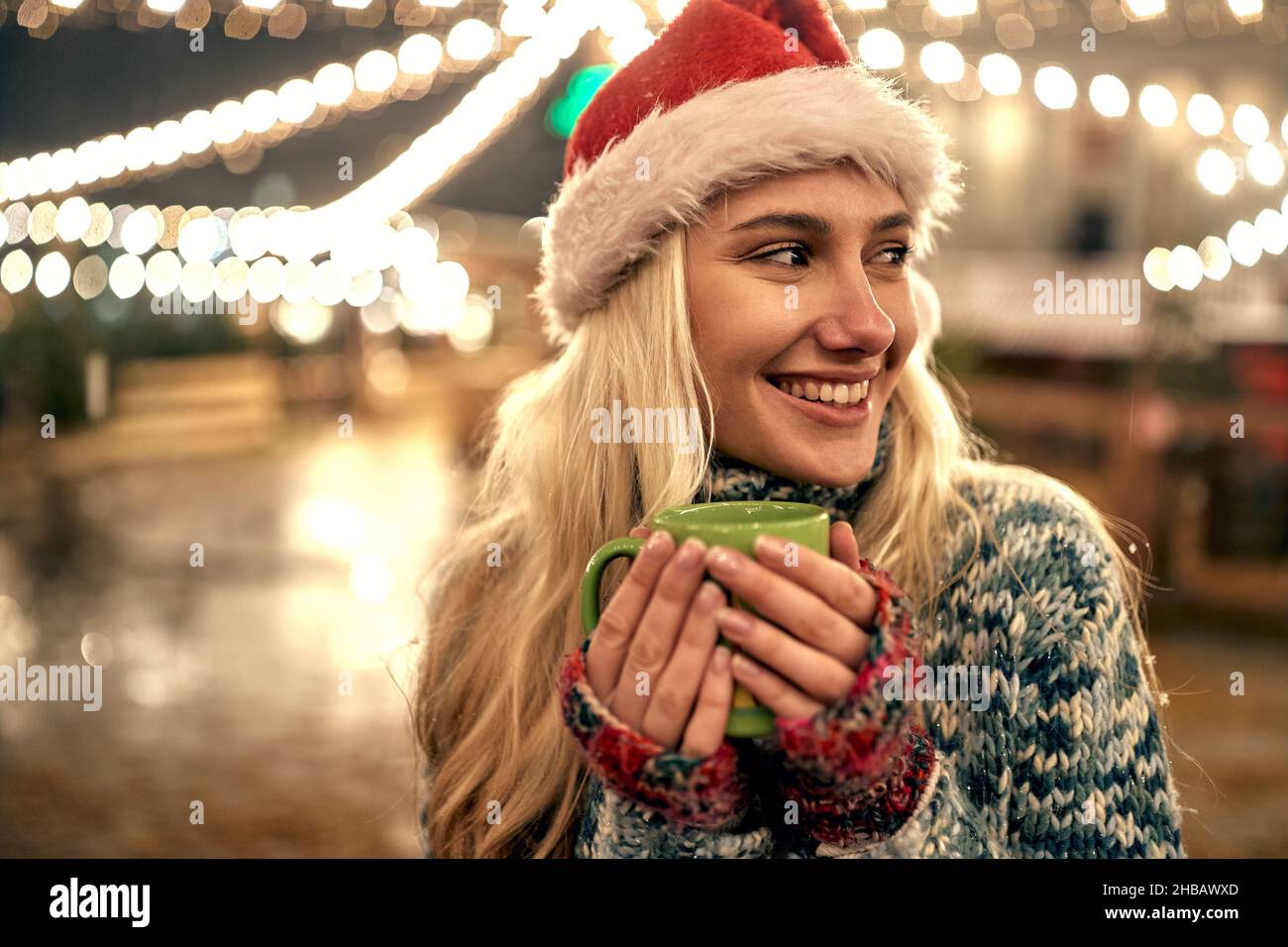young woman in santa hat drinking hot tea at a fair in Christmas Stock Photo